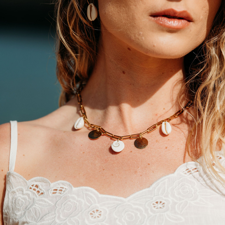 Close-up of a woman wearing a necklace with circular pendants against a blurred natural background