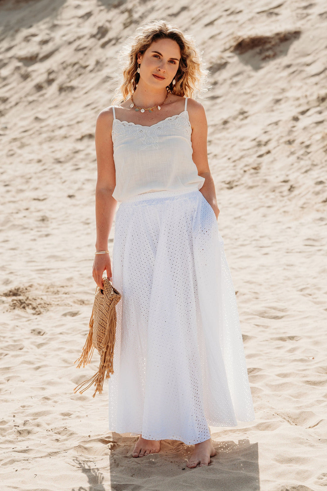 Woman in a white outfit standing on a sandy beach