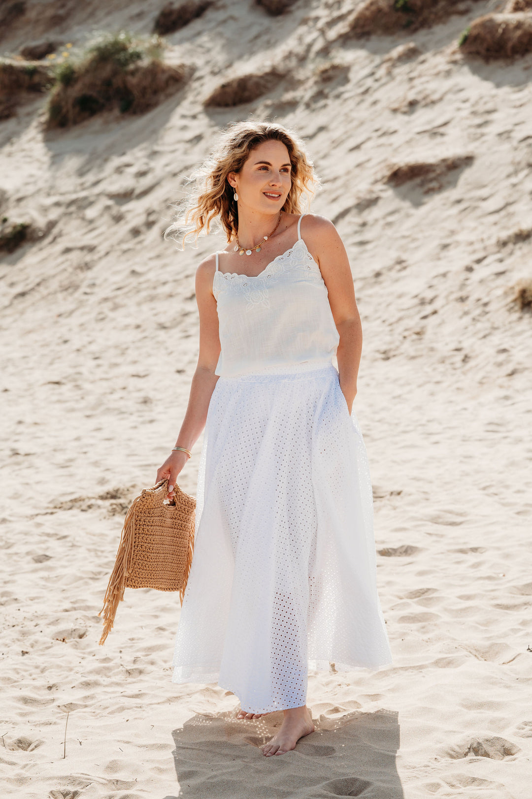 Woman in a white dress standing on a sandy beach