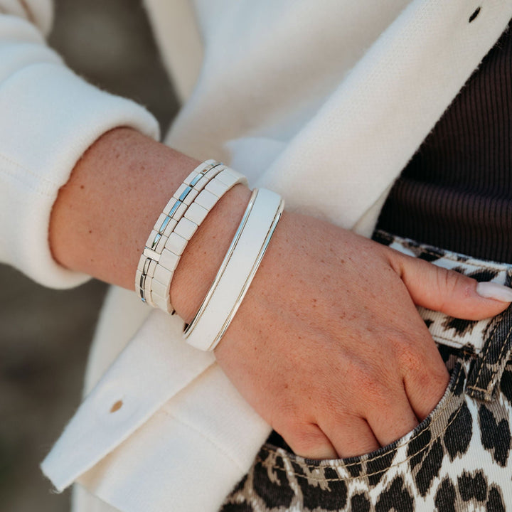 Close-up of a person's wrist with multiple bracelets on a blurred background