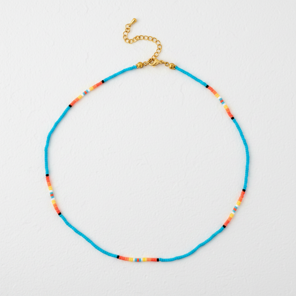 A beaded necklace with a bright turquoise blue main strand, accented by small segments of orange, yellow, red, and black beads, finished with a gold-tone clasp and extender chain, shown on a plain white background.