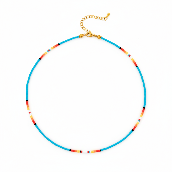 A beaded necklace with a bright turquoise blue main strand, accented by small segments of orange, yellow, red, and black beads, finished with a gold-tone clasp and extender chain, shown on a plain white background.