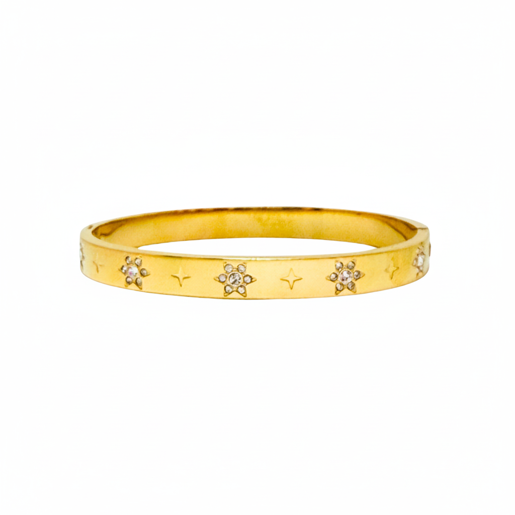 A gold bangle bracelet featuring a textured outer surface decorated with small star engravings and several flower motifs set with clear stones, shown against a plain white background.