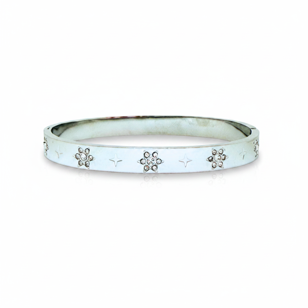 A silver-toned bangle bracelet with a smooth, polished finish, featuring small star engravings and three floral motifs set with clear rhinestones along the front edge, shown against a plain white background.