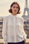 Woman wearing a white blouse with intricate patterns in front of the Eiffel Tower.