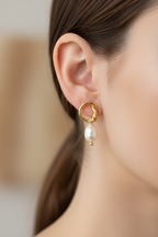 Gold earrings with pearl drops on a white background