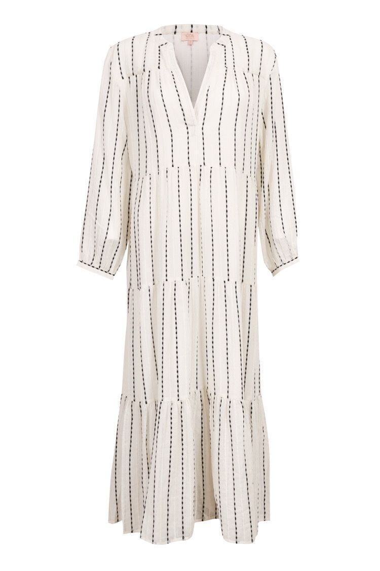 An off-white midi dress with vertical black dotted stripes, featuring a V-neckline, long sleeves, and a tiered ruffle hem.