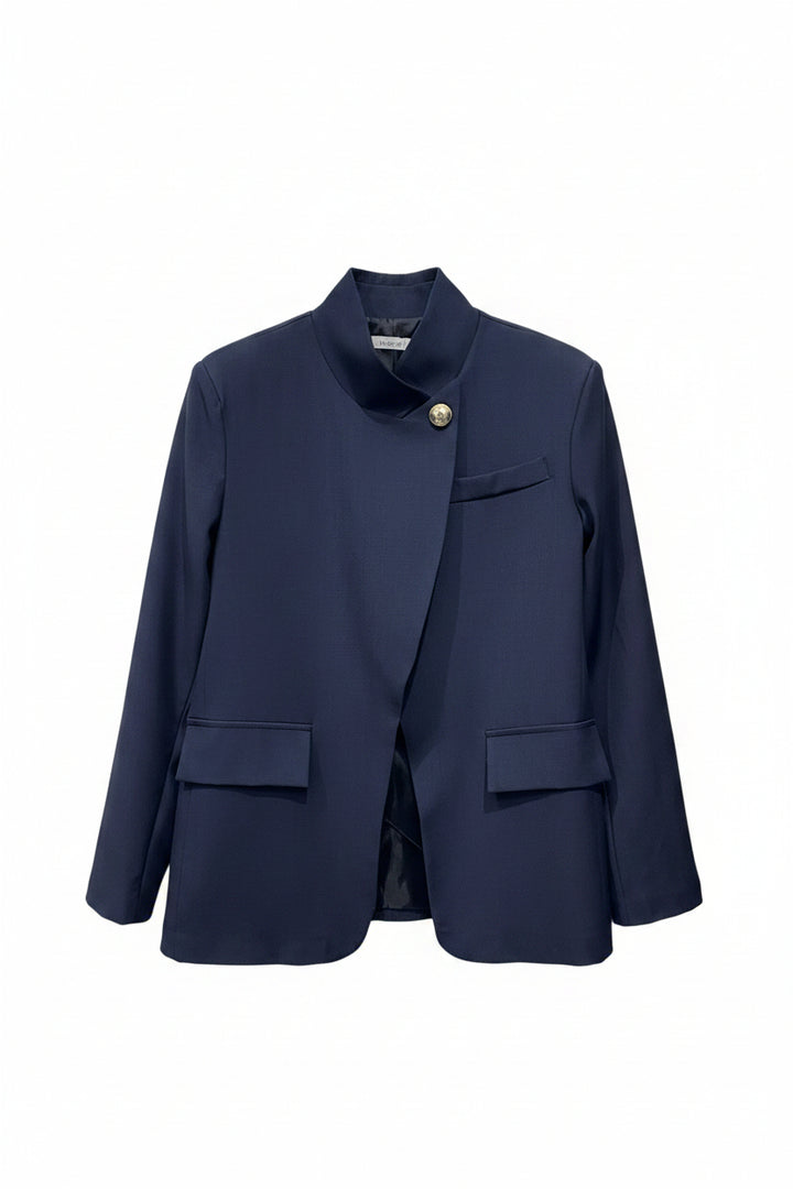 Navy blue blazer on a hanger against a white brick wall background