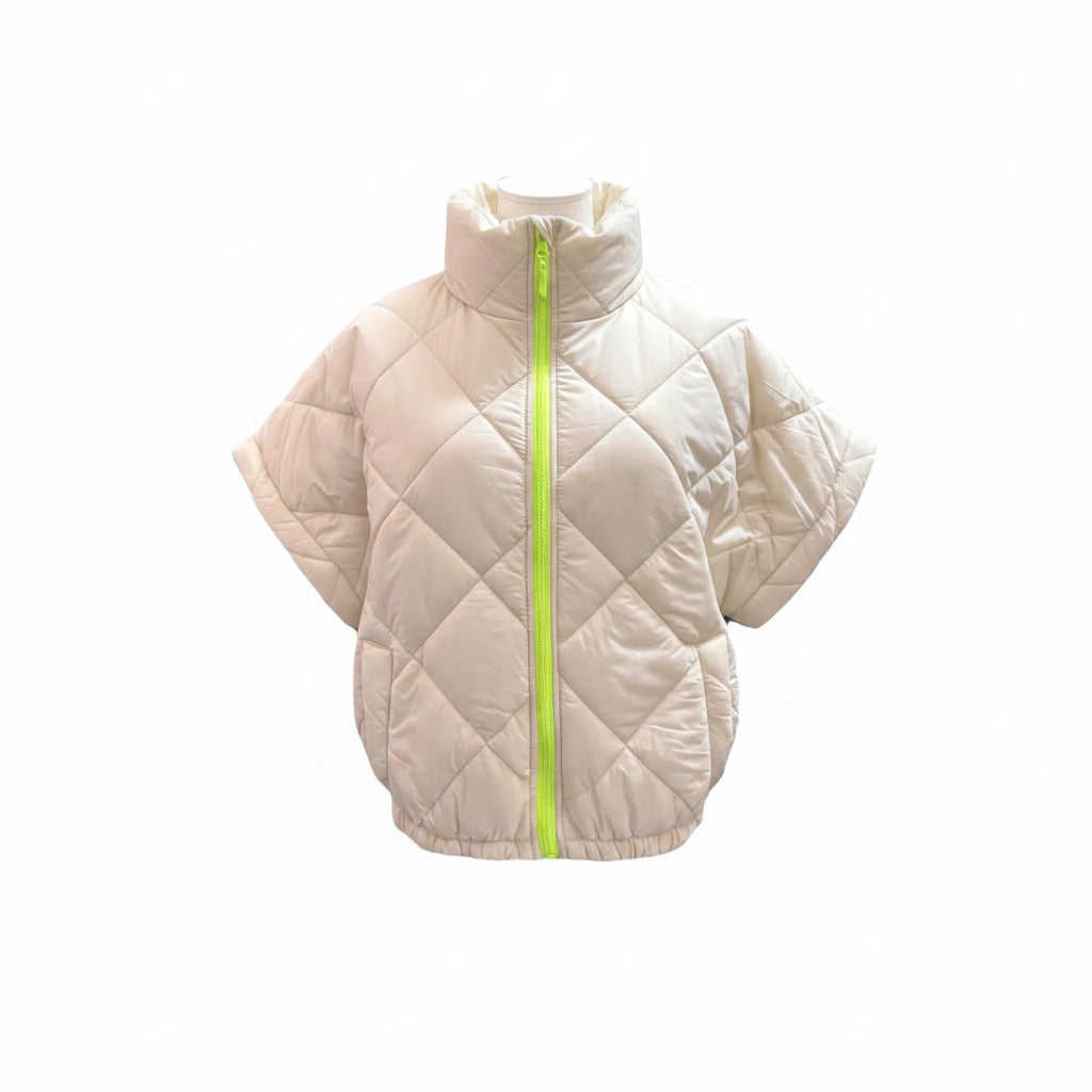 Mannequin wearing a beige quilted poncho with a green zipper on a white background