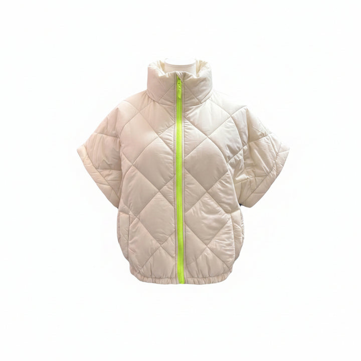 Mannequin wearing a beige quilted poncho with a green zipper on a white background