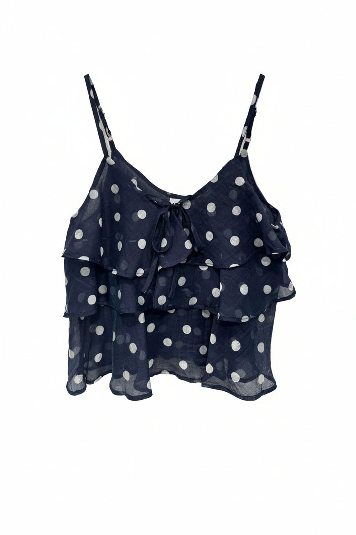 Navy blue top with white polka dots on a hanger against a white background