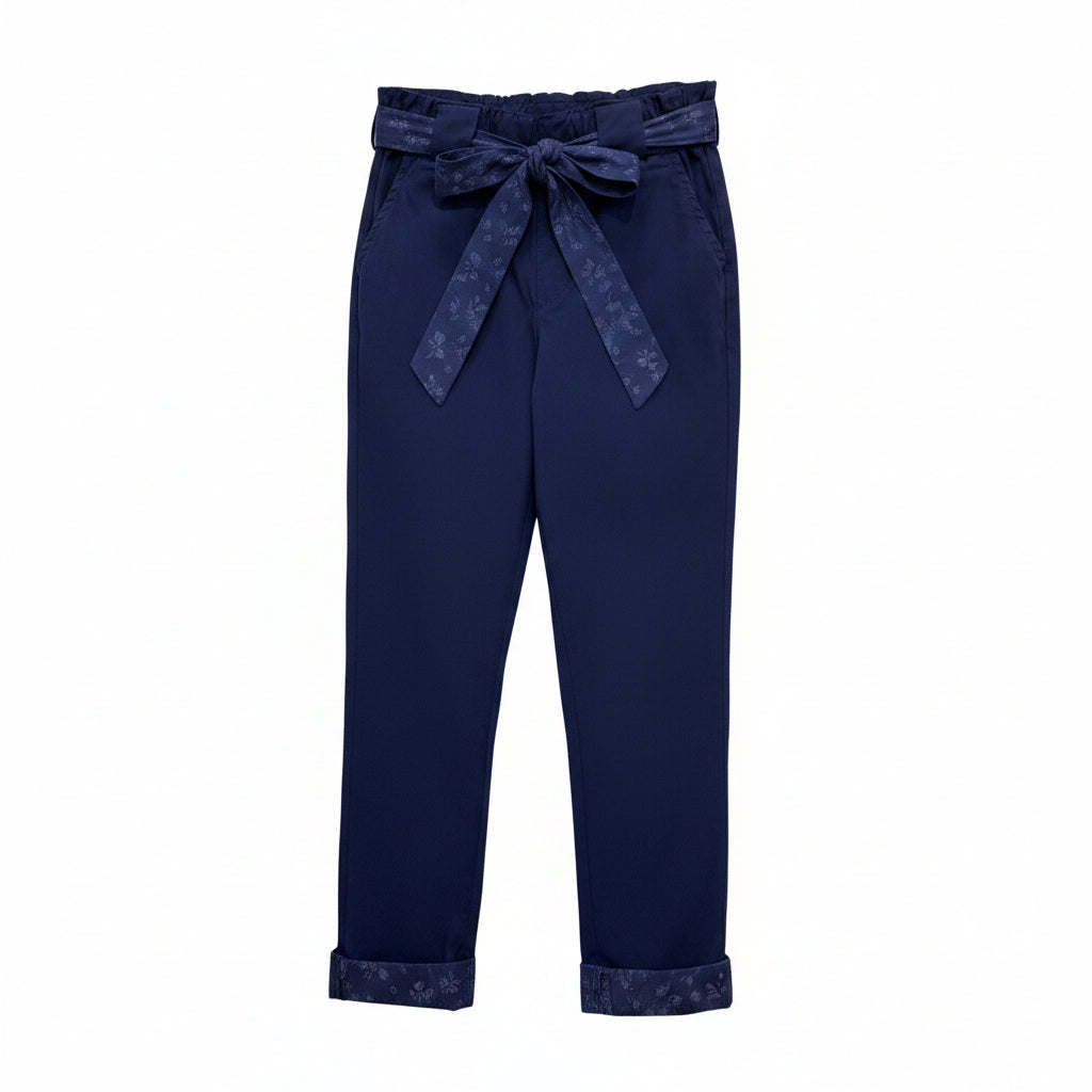 Dark navy blue cropped pants with a matching fabric tie belt at the elastic waist, hanging on a wooden hanger against a plain white wall.