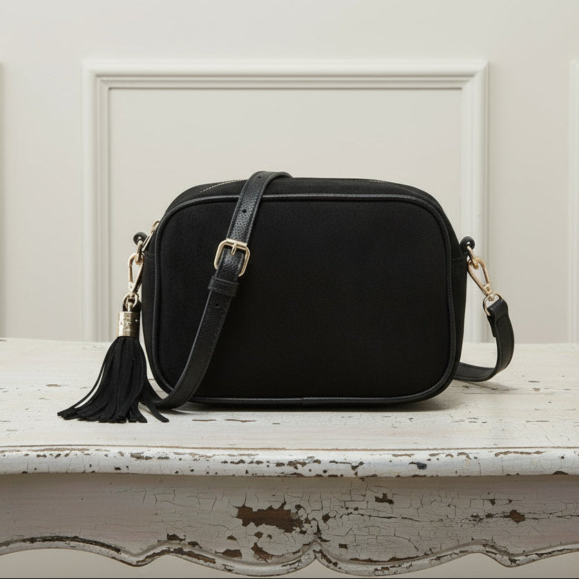 Black crossbody bag with tassel on a white background