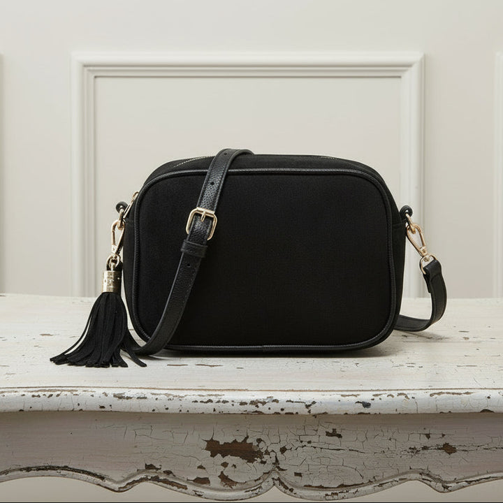 Black crossbody bag with tassel on a white background